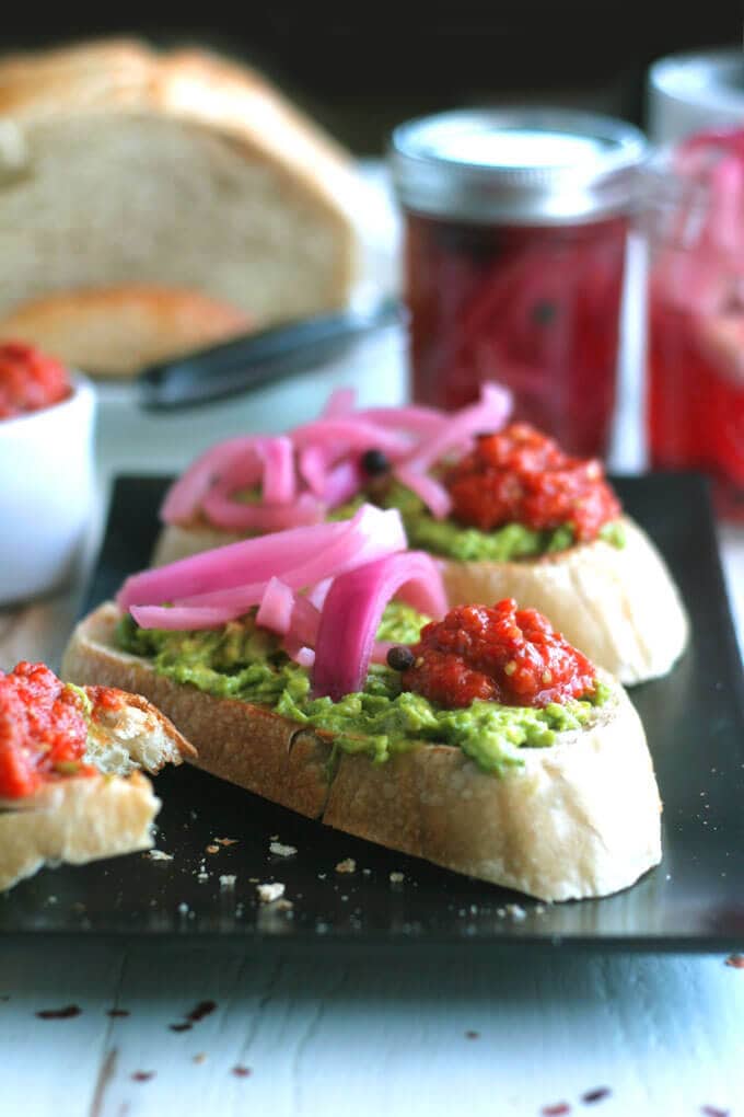 A close up of a plate of tartines with Ajvar and Onion