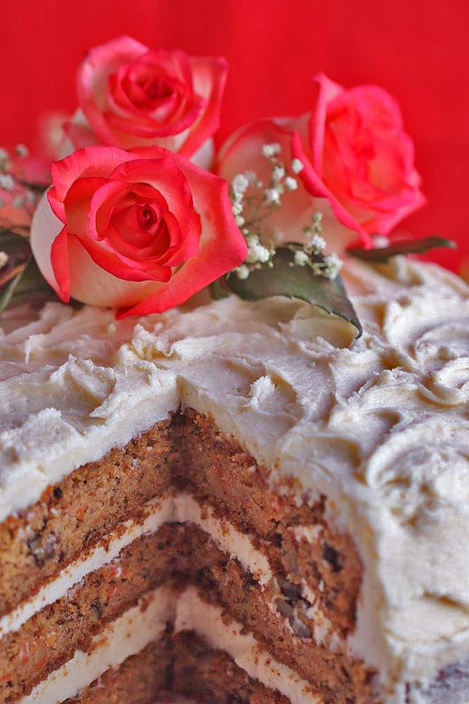 A close up of top of a cake and roses with slice removed