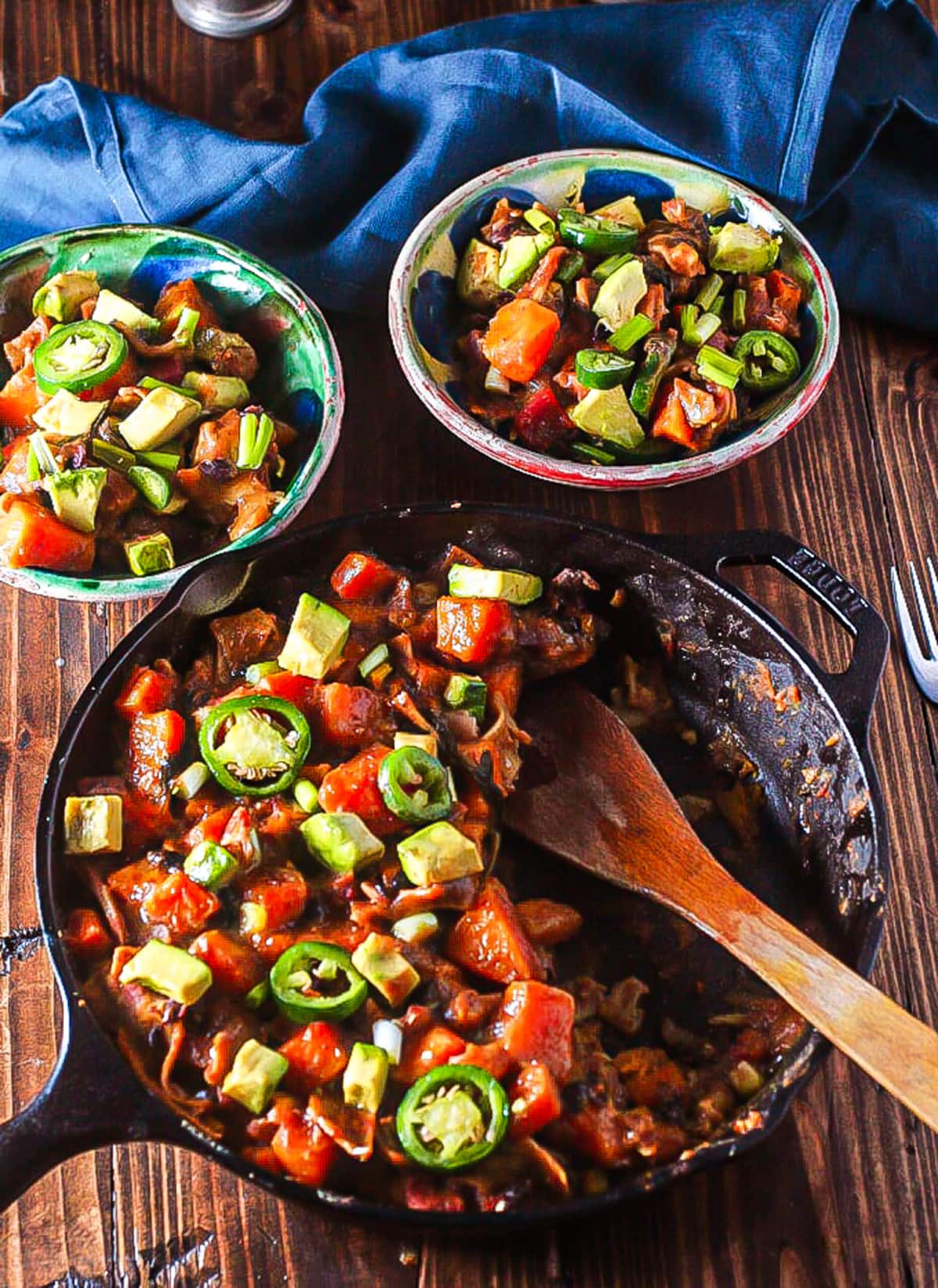vegan enchiladas in cast iron skillet surrounded by two bowls full of vegan enchilada recipe