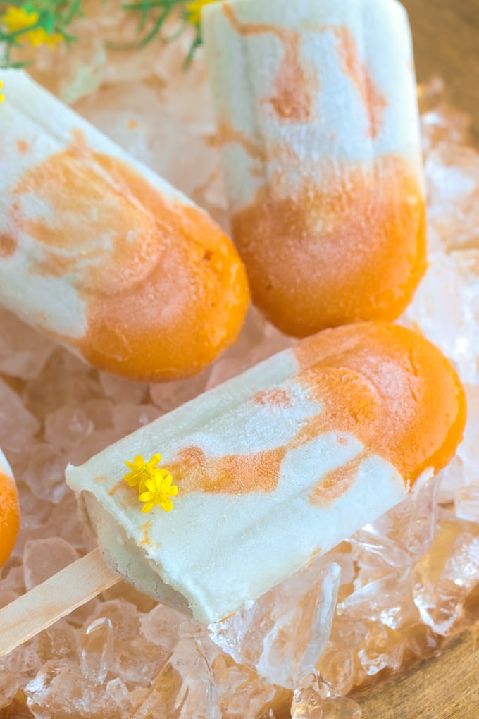 3 orange and white popsicles on a bed of ice