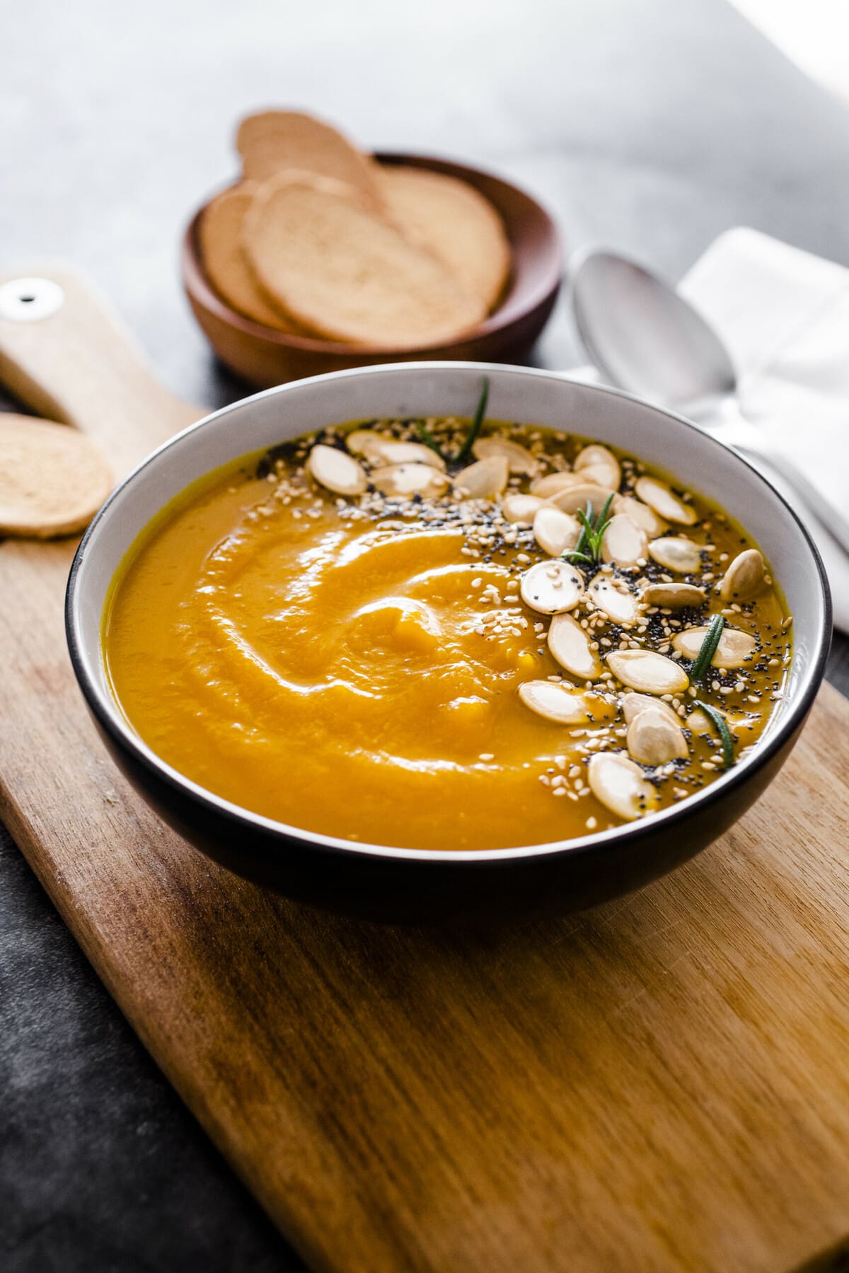 side view of creamy chickpea soup garnished with seeds on a cutting board