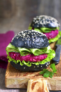 two beet burgers on black buns with sesame seeds
