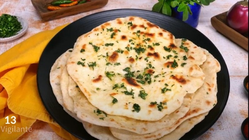 step 13 showing stack of easy vegan naan bread on a black plate on top of a table 