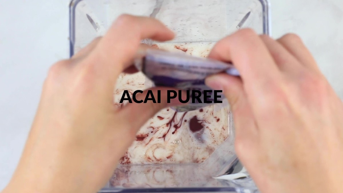 person squeezing packet of frozen acai into blender.