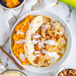 a bowl of oatmeal topped with sweet potatoes, bananas, pecans and coconut cream