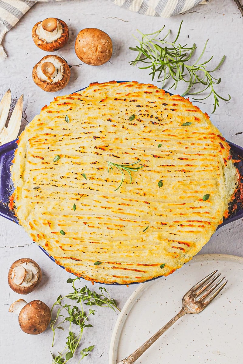 overhead view of whole vegan shepherd's pie in a blue dish on a white table