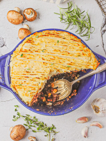 overhead view of Shepherd's pie with slice removed in a blue casserole dish on a white table